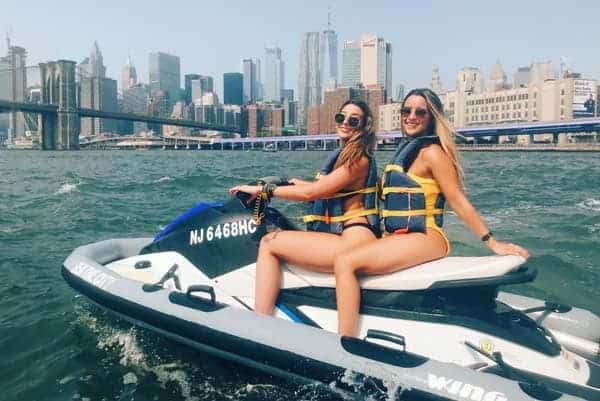 women with life jackets on jet skis